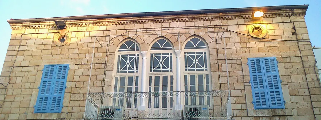 An old stone house with arched windows and blue shutters in Jounieh's souk