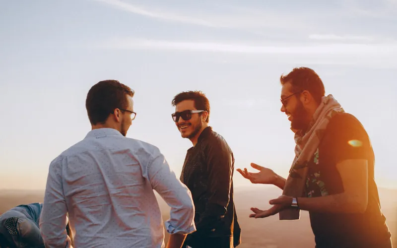 Three friends laughing while one tells a story with his hands